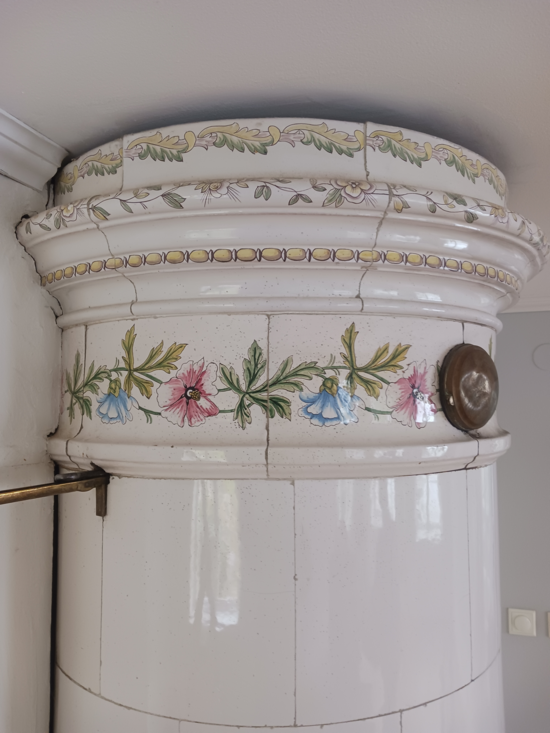 Vit rund kakelugn med blommor