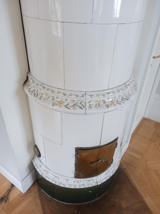 Vit rund kakelugn med blommor